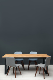 Modern empty wooden table near black wall