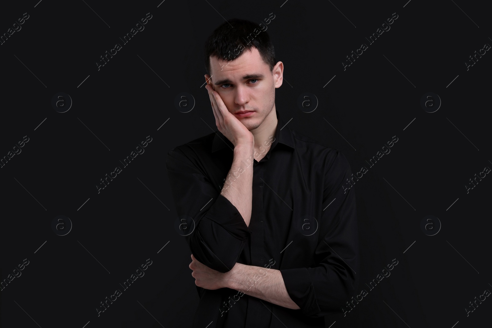 Photo of Portrait of sad man on black background