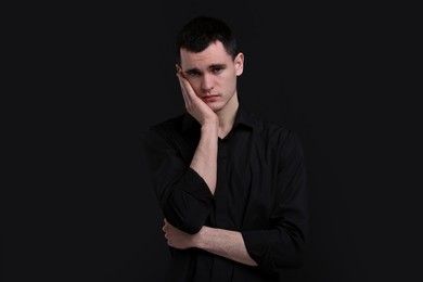 Portrait of sad man on black background