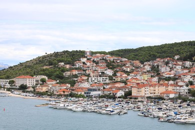 Photo of Picturesque view of town with buildings, moored boats and sea on cloudy day