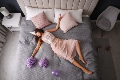 Photo of Exhausted woman in festive outfit sleeping on bed at home after party, above view