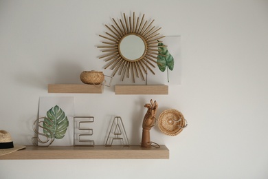 Wooden shelves with women's accessories and different decorative elements on light wall. Space for text