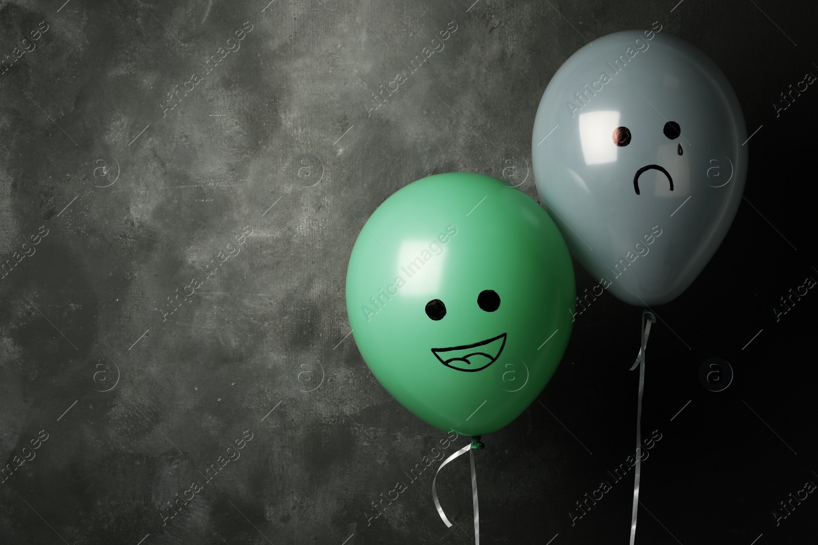 Photo of Balloons with drawings of sad and happy faces on dark background, space for text. Depression symptoms