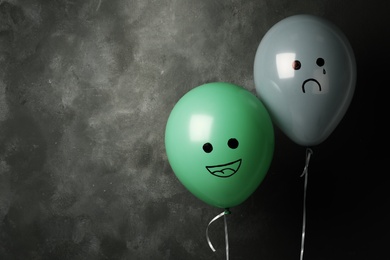 Photo of Balloons with drawings of sad and happy faces on dark background, space for text. Depression symptoms