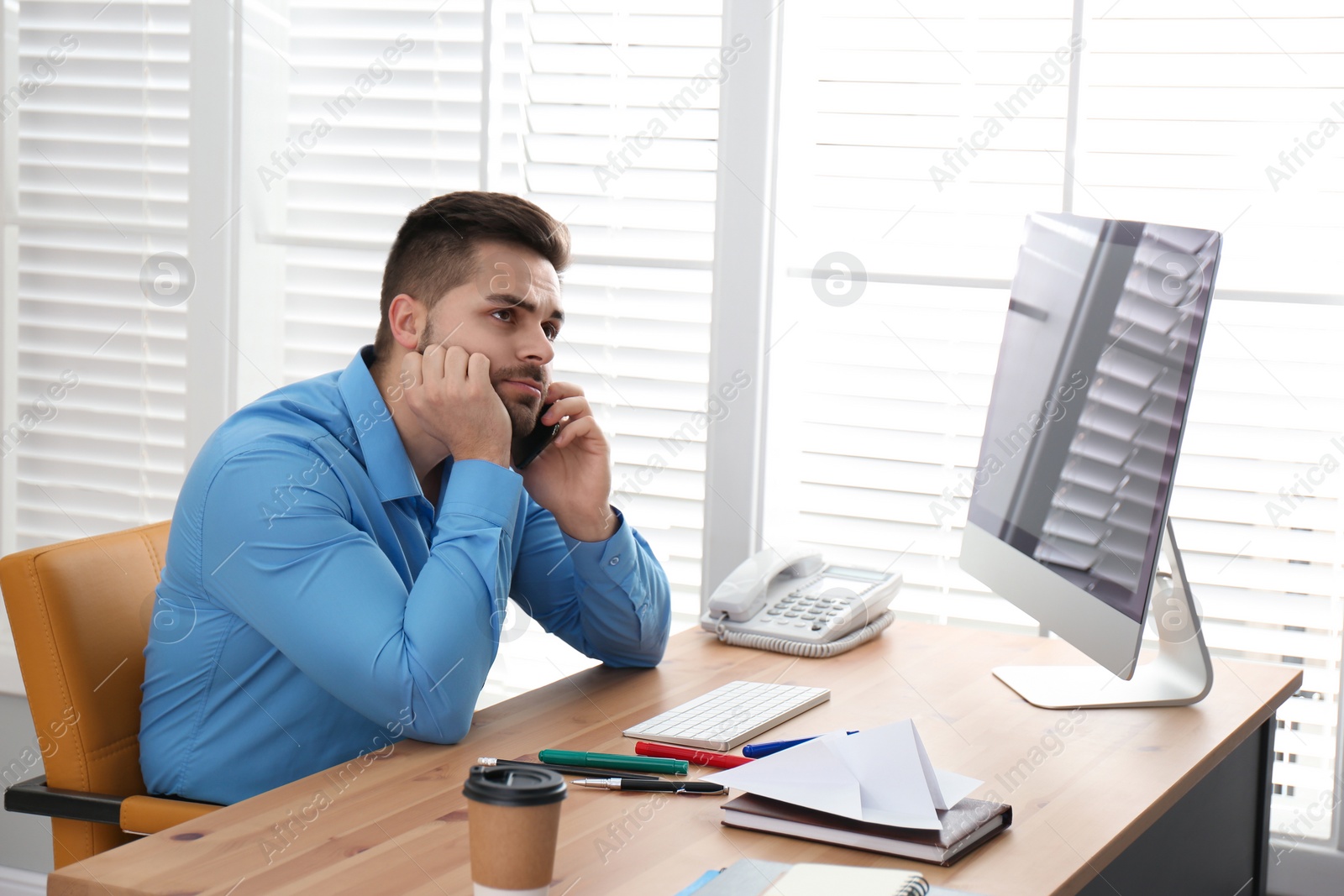 Photo of Lazy employee talking on smartphone at table in office