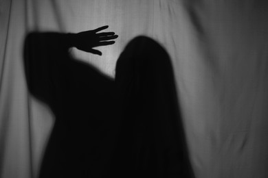 Photo of Silhouette of creepy ghost behind grey cloth