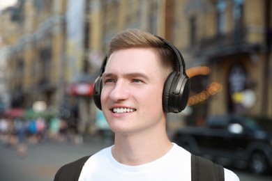 Photo of Smiling man in headphones listening to music outdoors