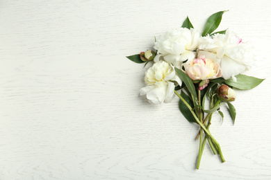 Photo of Beautiful peonies on white wooden table, flat lay. Space for text