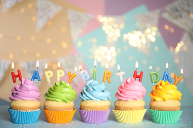 Photo of Birthday cupcakes with burning candles on grey table