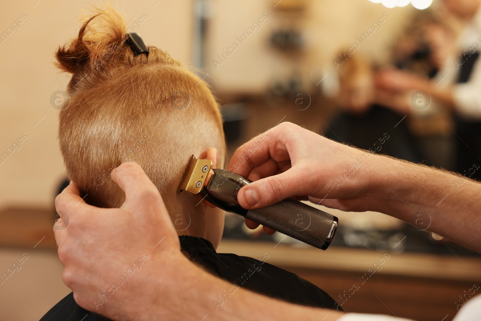 Photo of Professional hairdresser cutting boy's hair in beauty salon, closeup