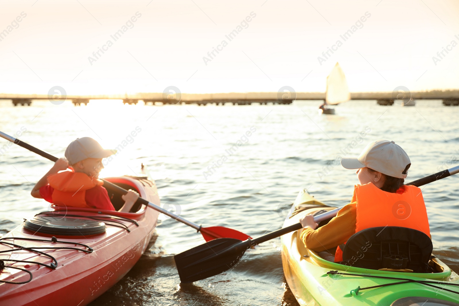Photo of Little children kayaking on river, back view. Summer camp activity