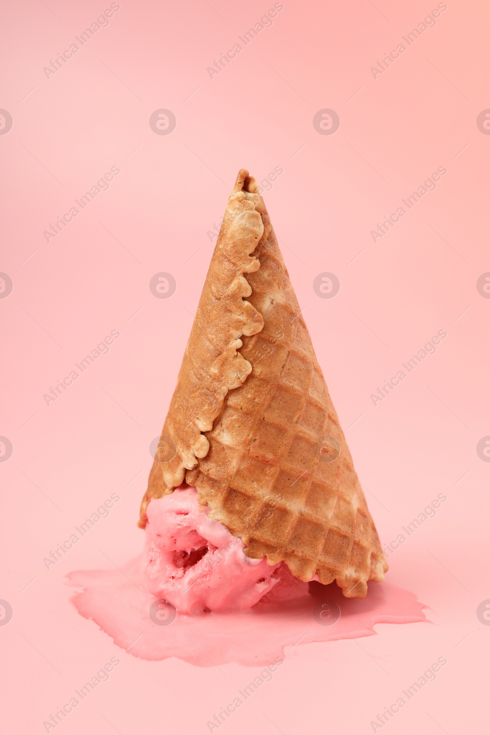 Photo of Melted ice cream in wafer cone on pink background