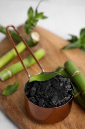 Photo of Fresh bamboo and charcoal on wooden board, closeup