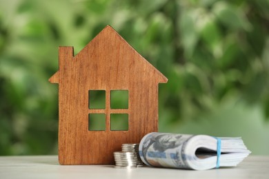 Photo of Mortgage concept. House model and money on white table against blurred background, closeup