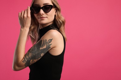 Photo of Beautiful woman with tattoos on arm against pink background. Space for text