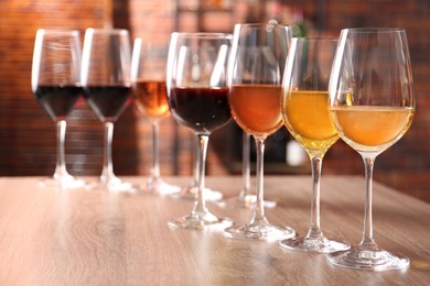 Different tasty wines in glasses on wooden table, space for text