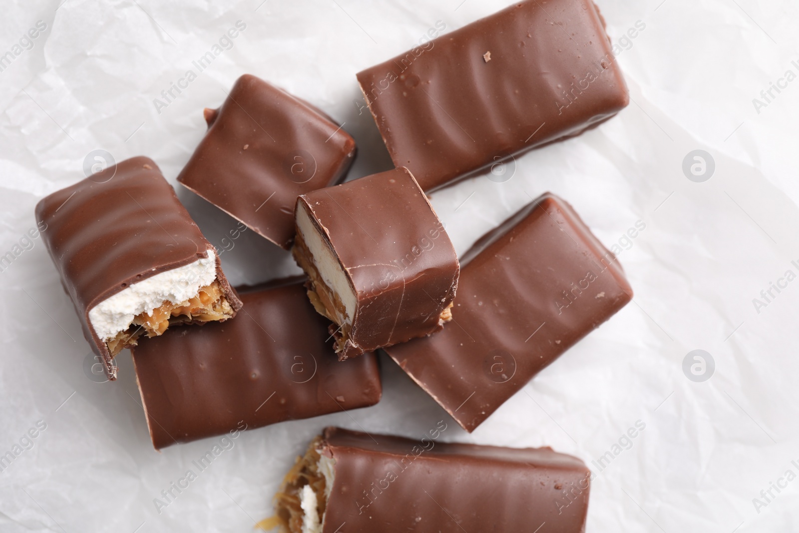 Photo of Tasty chocolate bars with nougat on white table, top view