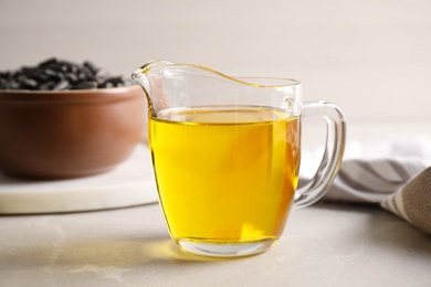 Photo of Glass jug with sunflower oil on light grey marble table