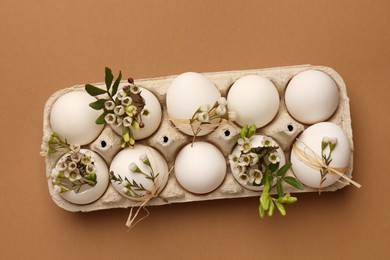 Festive composition with eggs and floral decor on brown background, top view. Happy Easter