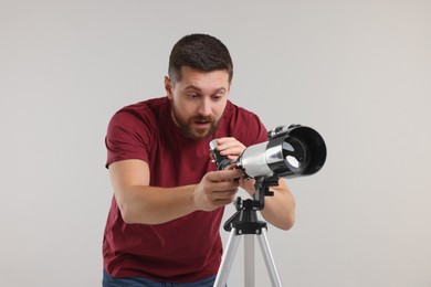 Excited astronomer with telescope on light grey background