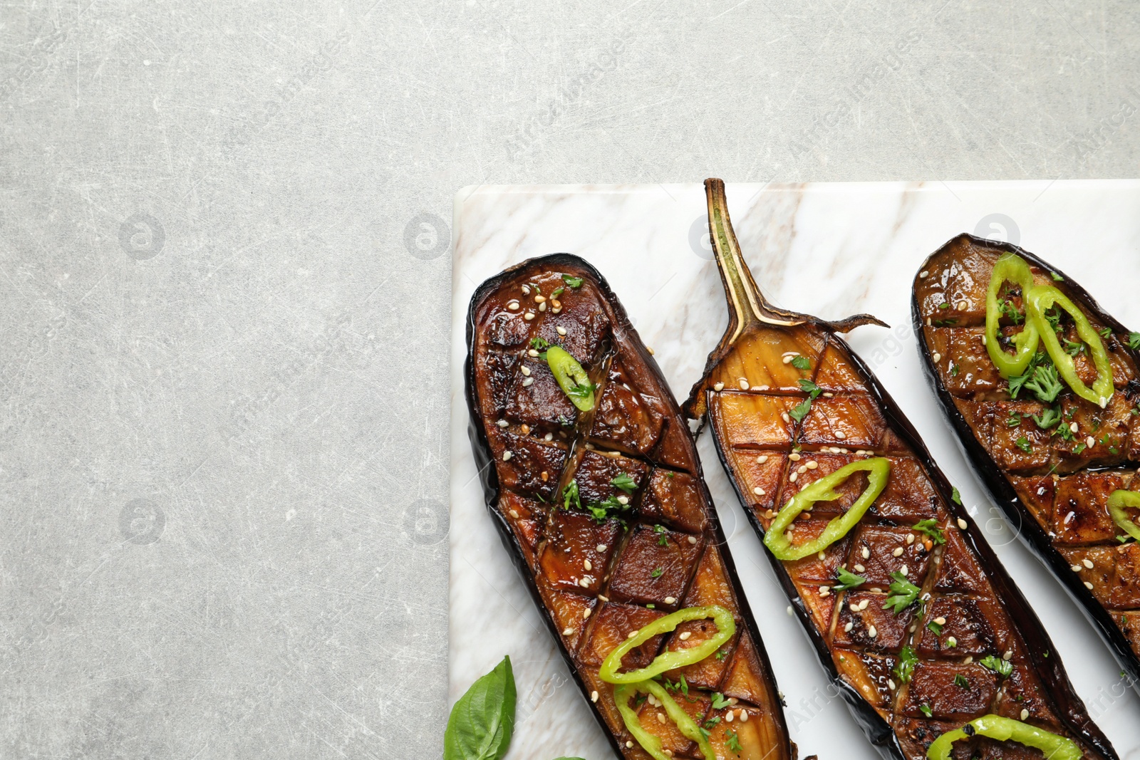 Photo of Board with fried eggplant slices on grey background, top view. Space for text