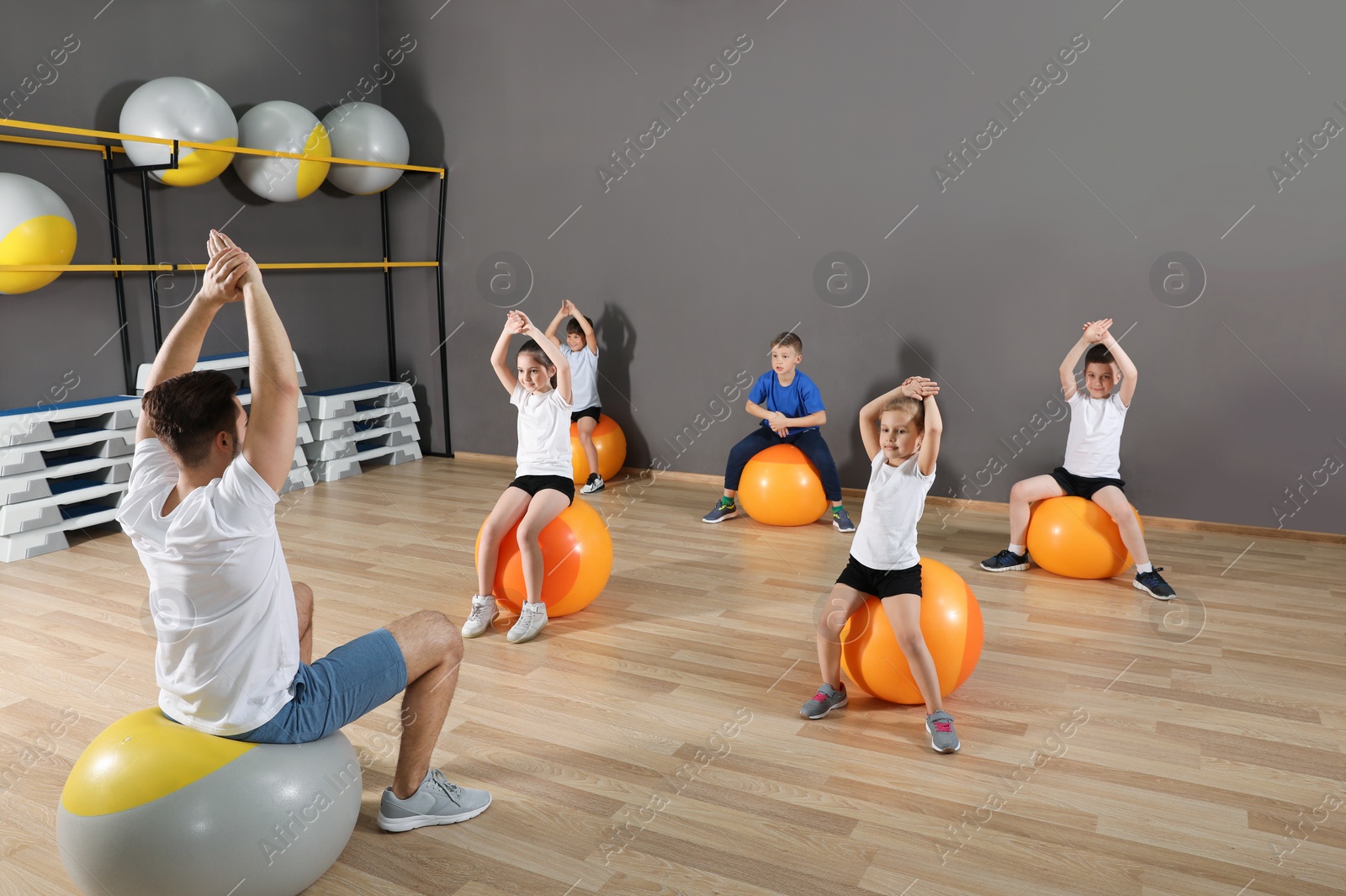 Photo of Cute little children and trainer doing physical exercise in school gym. Healthy lifestyle