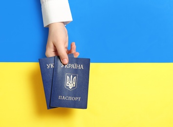 Photo of Woman holding Ukrainian internal passports over national flag, top view. Space for text