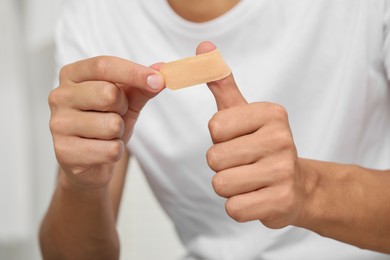 Photo of Man putting sticking plaster onto thumb, closeup