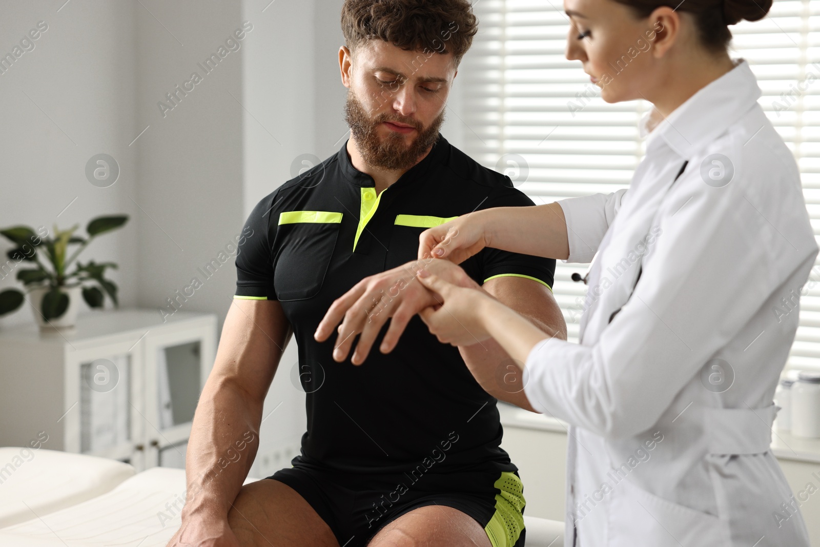 Photo of Doctor in uniform examining injured sportsman in hospital