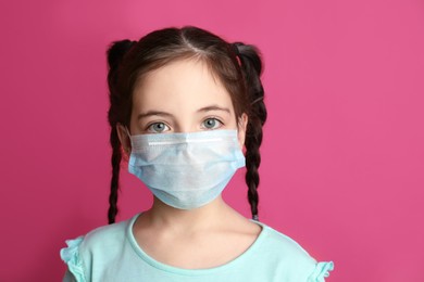 Girl wearing protective mask on pink background. Child's safety from virus