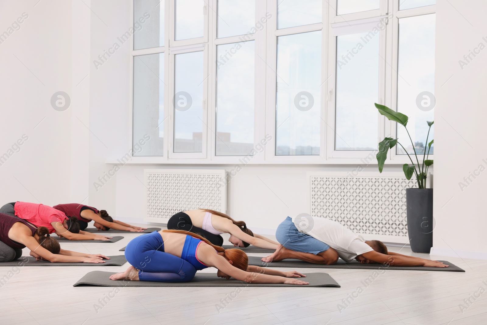 Photo of Group of people practicing yoga on mats indoors