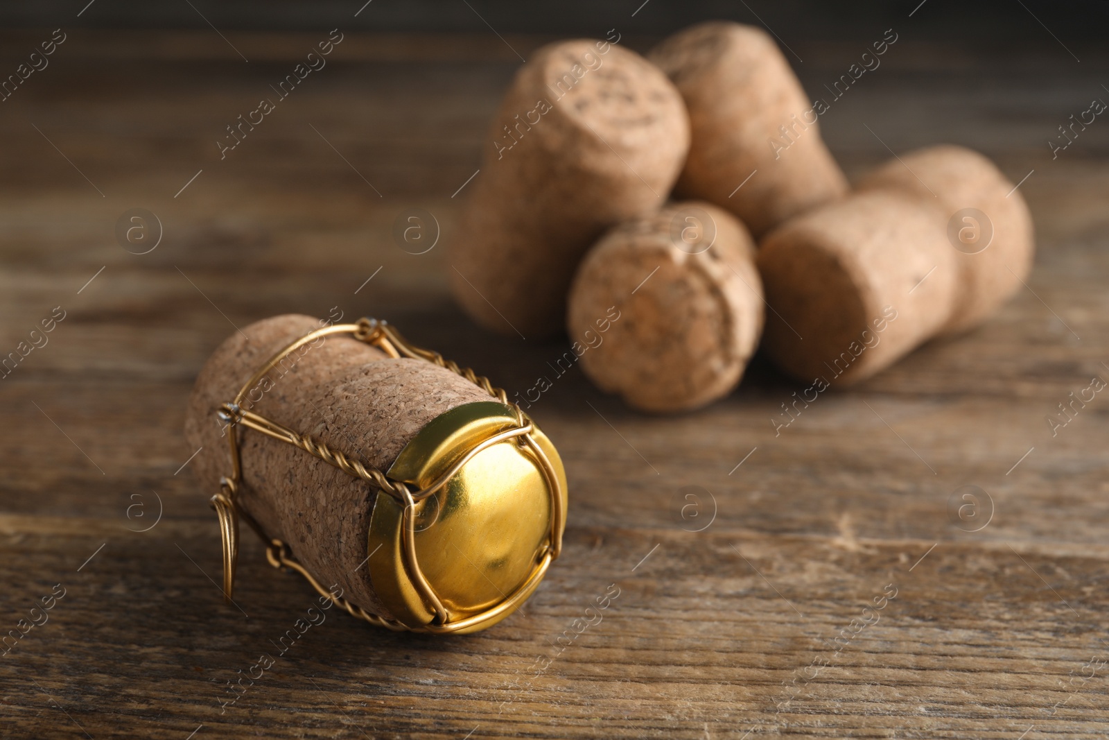 Photo of Cork of sparkling wine and muselet cap on wooden table, closeup. Space for text