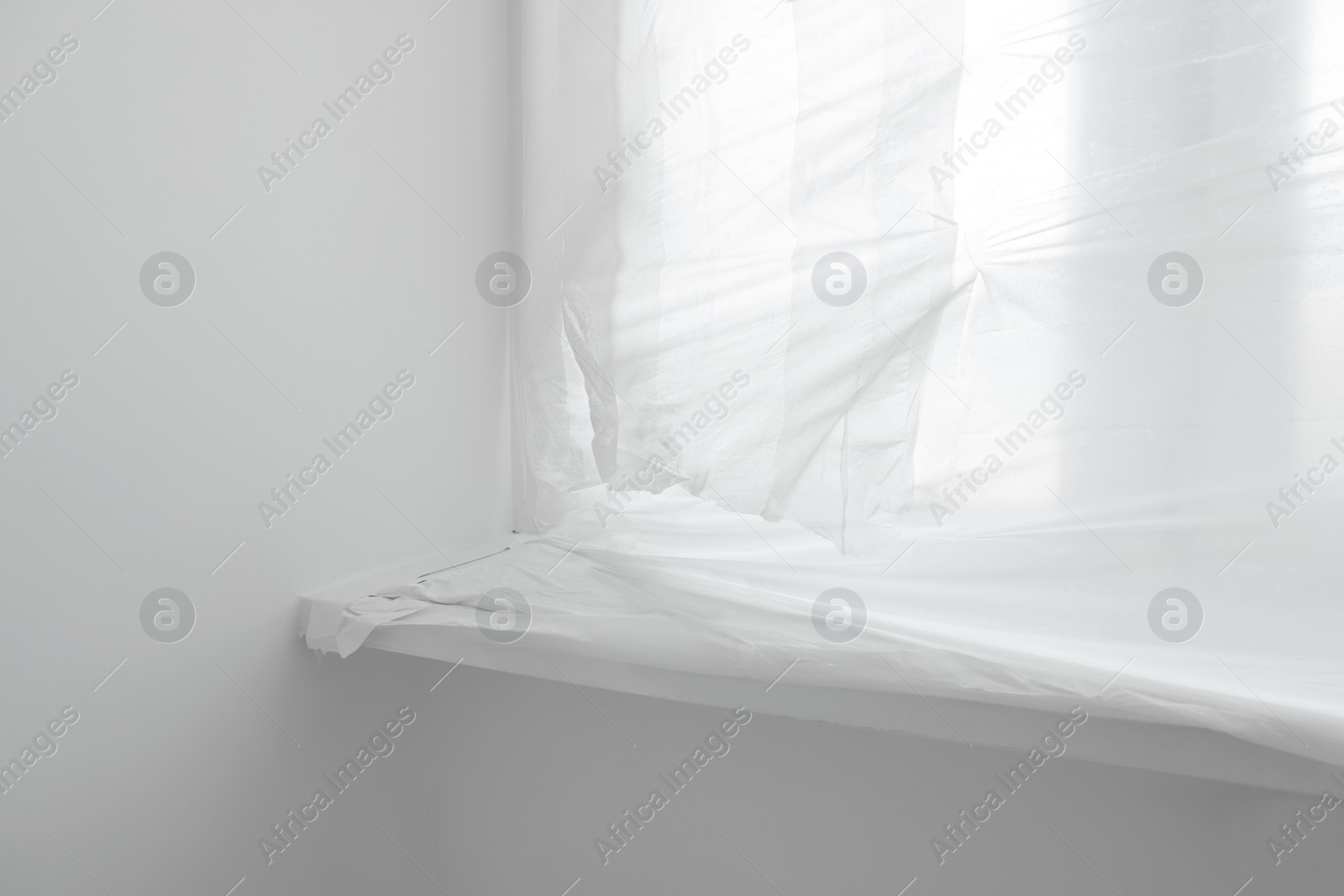 Photo of Window and sill covered with plastic film indoors