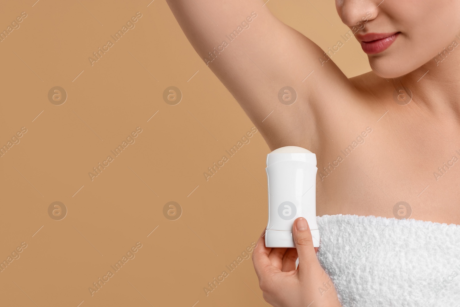 Photo of Woman applying deodorant on beige background, closeup. Space for text