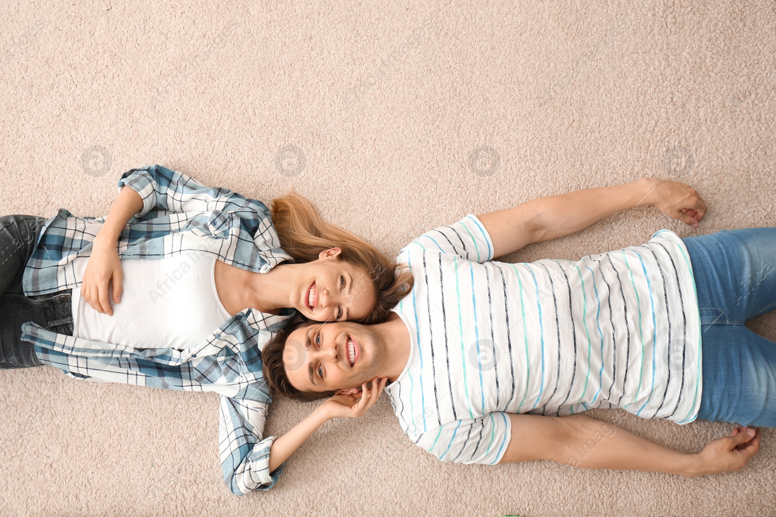 Photo of Lovely young couple lying on cozy carpet at home