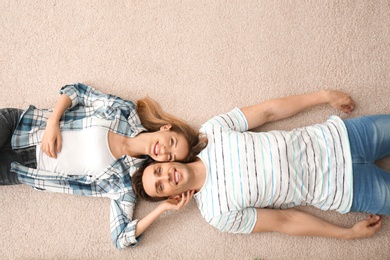 Lovely young couple lying on cozy carpet at home