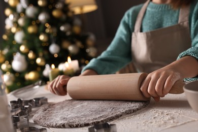 Little child rolling dough for Christmas cookies at white wooden table indoors, closeup