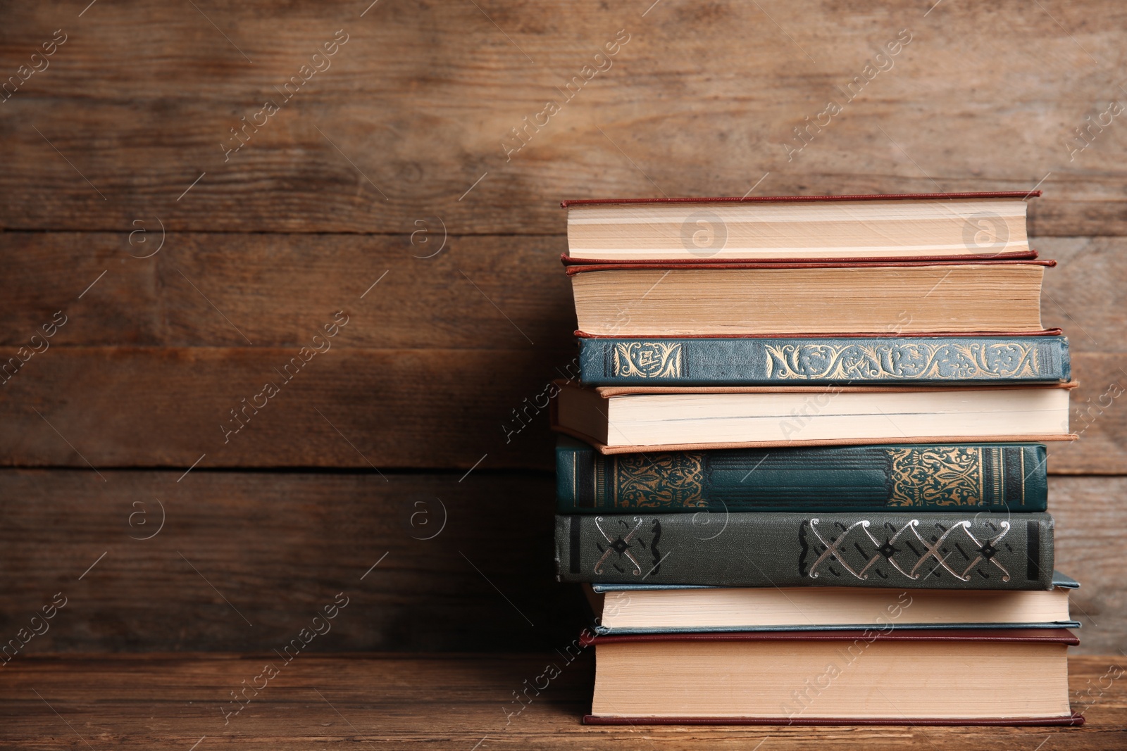 Photo of Collection of different books on table against wooden background. Space for text