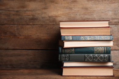 Photo of Collection of different books on table against wooden background. Space for text