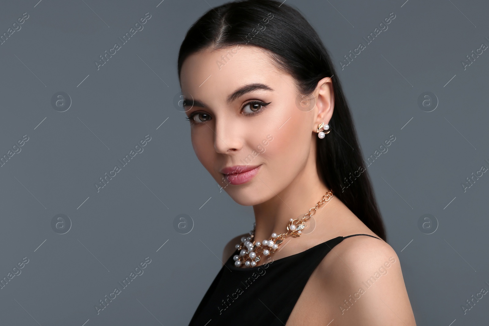 Photo of Beautiful young woman with elegant jewelry on dark grey background