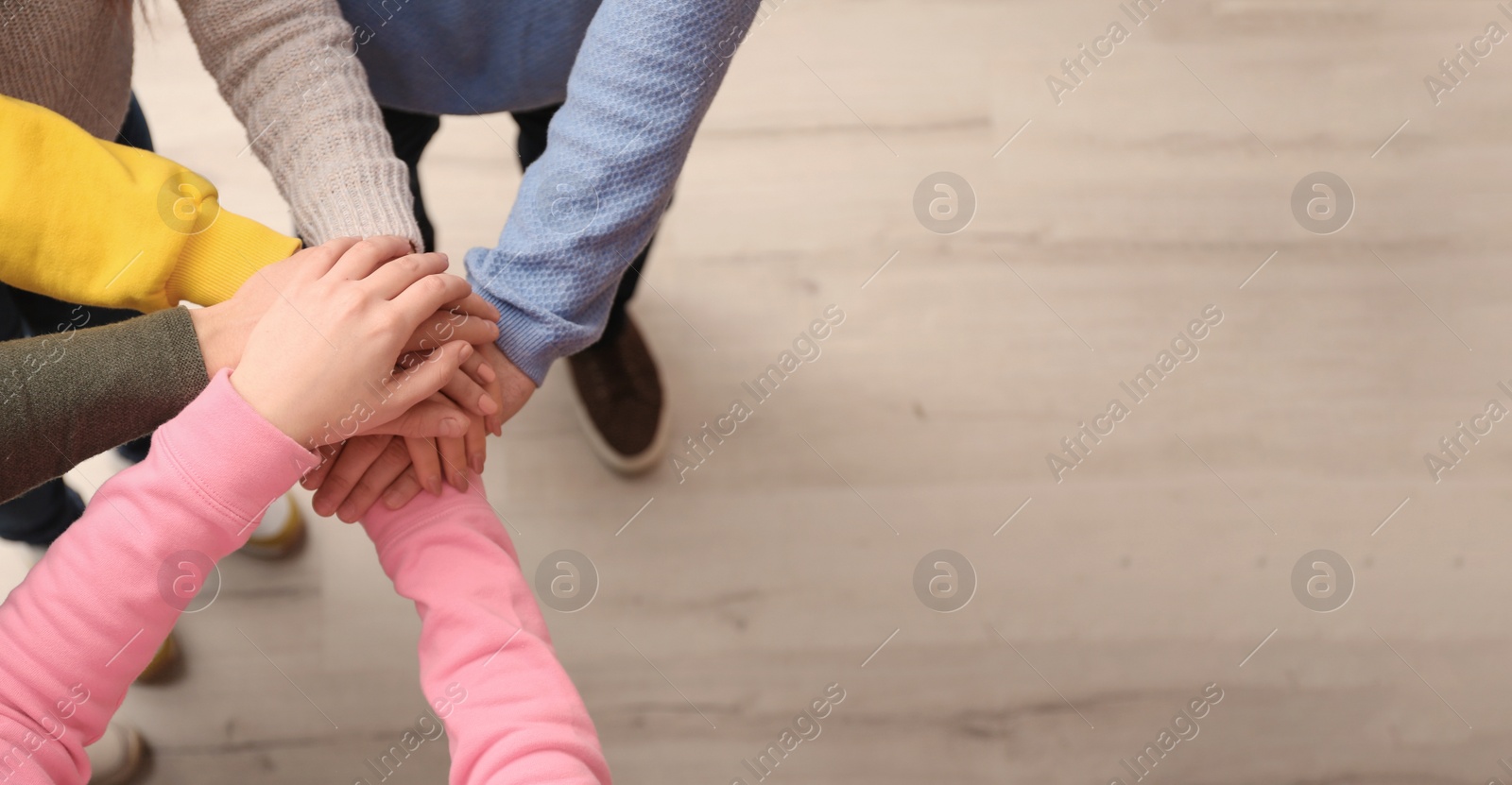 Photo of Group of people holding their hands together indoors, top view. Space for text