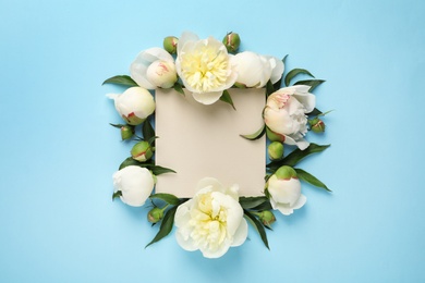 Fragrant peonies and blank card on color background, flat lay with space for text. Beautiful spring flowers