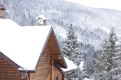Photo of Wooden cottage with snowy roof. Winter vacation