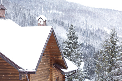 Wooden cottage with snowy roof. Winter vacation