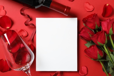 Photo of Flat lay composition with blank greeting card, wine and roses on red background. Valentine's day celebration