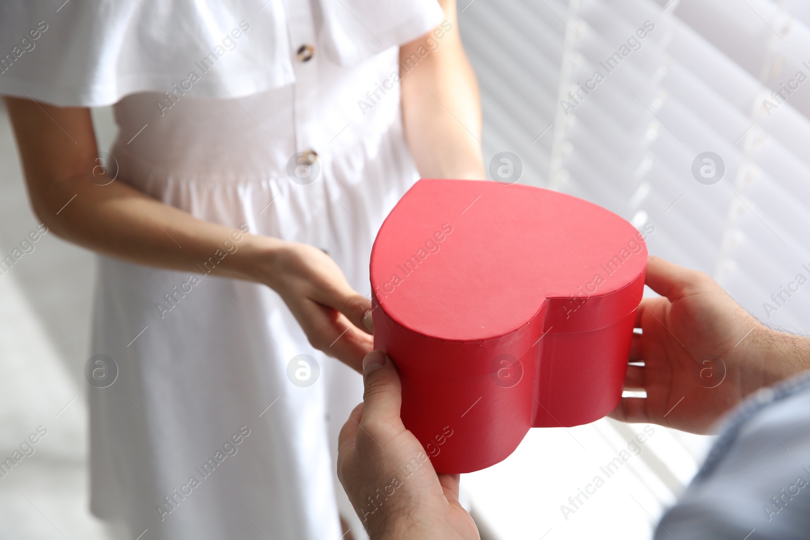 Photo of Man presenting gift to his beloved woman at home, closeup. Valentine's day celebration