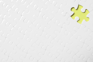 Photo of Blank white puzzle with missing piece on yellow background, top view. Space for text