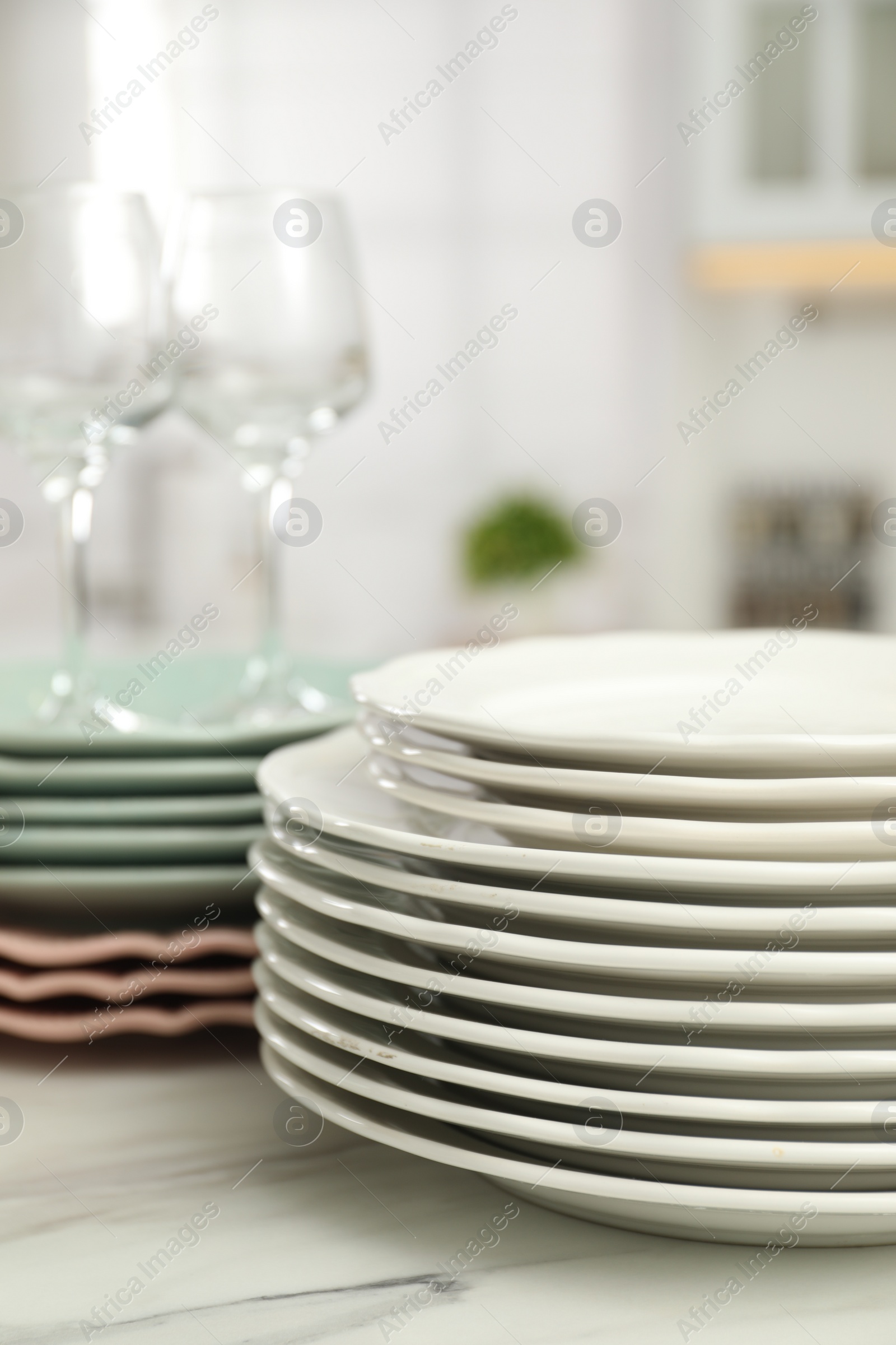 Photo of Clean plates and glasses on white marble table in kitchen