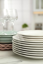 Clean plates and glasses on white marble table in kitchen