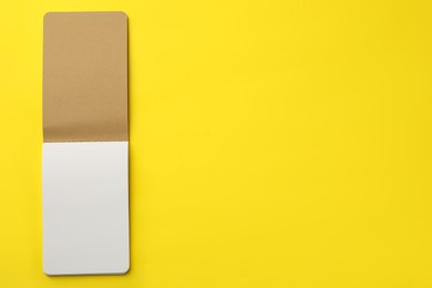 Photo of Stylish open notebook with blank sheets on yellow background, top view. Space for text